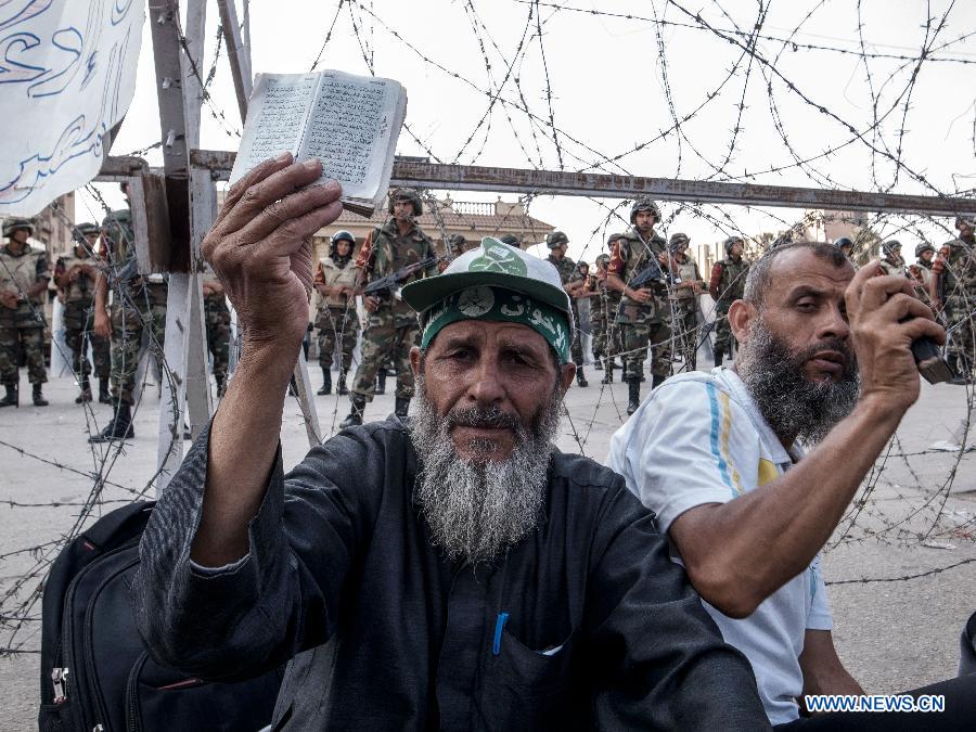 A supporter of Morsi holds up Quran as he attends sit-in outside the Republican Guards headquarters in Nasr city, Cairo, Egypt, July 6, 2013. (Xinhua/Li Muzi)