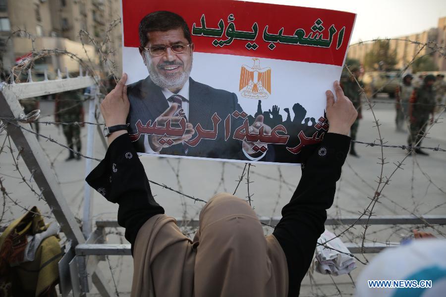 A supporters of ousted Egyptian President Mohamed Morsi holds up a poster of Morsi outside the Republican Guard headquarter, in Nasr City, Cairo, Egypt, July 6, 2013. (Xinhua/Wissam Nassar)