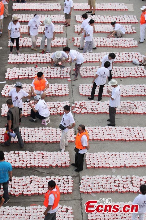 People prepare river lanterns in Northeast China's Jilin Province, July 7, 2013. Altogether 14,630 lanterns were released in the Songhua River, setting a new Guinness World Record.  (CNS/Cang Yan)