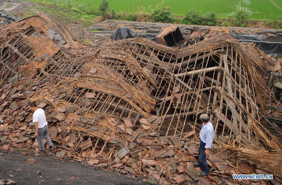 People walk past a house destroyed by a tornado at Nanfeng Village of Sanduo Township in Gaoyou City, east China's Jiangsu Province, July 7, 2013. A tornado hit Gaoyou around 4:40 p.m. Sunday, striking houses of more than 400 families and hurting over 50 people, seven of whom were severely wounded. (Xinhua/Wang Zhuo)