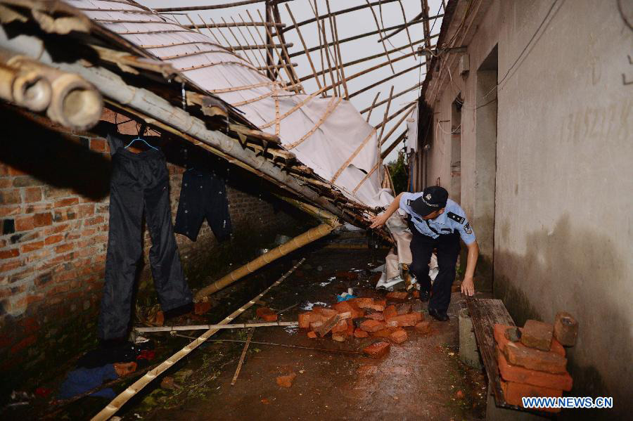 A police officer searches for people trapped under a house destroyed by a tornado at Nanfeng Village of Sanduo Township in Gaoyou City, east China's Jiangsu Province, July 7, 2013. A tornado hit Gaoyou around 4:40 p.m. Sunday, striking houses of more than 400 families and hurting over 50 people, seven of whom were severely wounded. (Xinhua/Wang Zhuo)