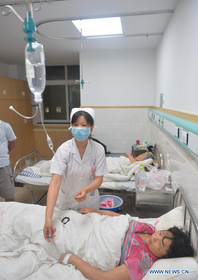 A nurse provides medical service to people hurt in a tornado in Gaoyou City, east China's Jiangsu Province, July 7, 2013. A tornado hit Gaoyou around 4:40 p.m. Sunday, striking houses of more than 400 families and hurting over 50 people, seven of whom were severely wounded. (Xinhua/Wang Zhuo)