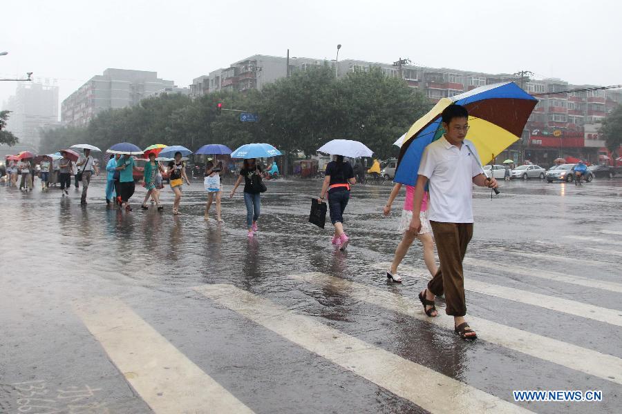 People walk in rain on the flooded Guangcai Road in the Fengtai District of Beijing, capital of China, July 8, 2013. Beijing was hit by a thunder storm Monday morning. Rainfall is expected to continue in the next three days, according to the local meteorological authority. (Xinhua/Wang Yueling)