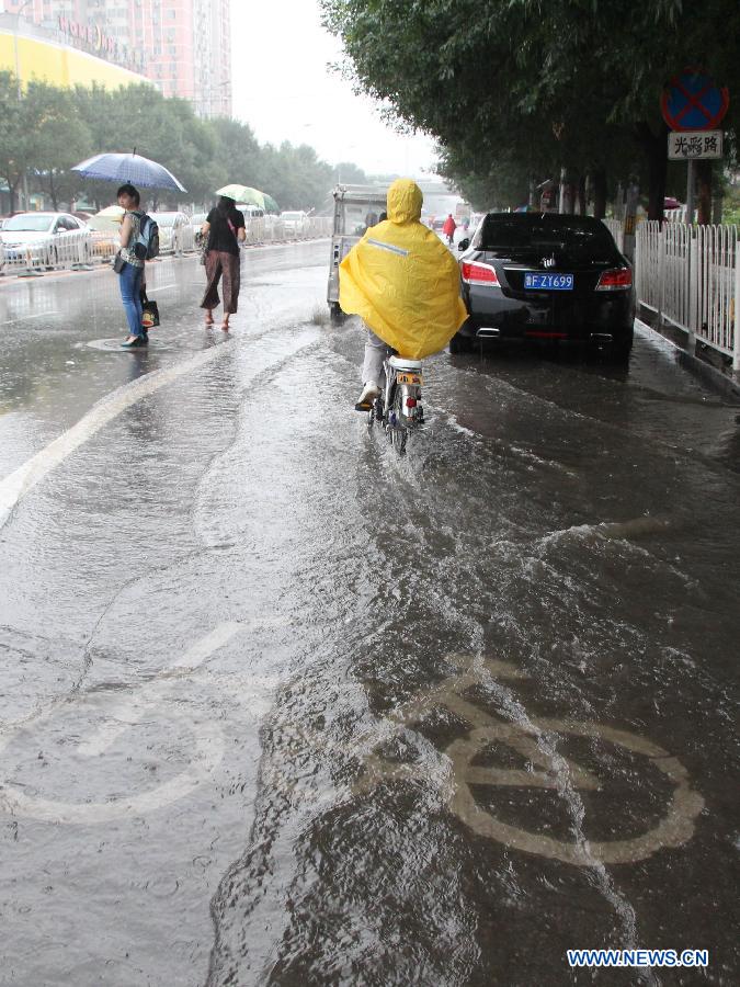 People are seen in rain on the flooded Guangcai Road in the Fengtai District of Beijing, capital of China, July 8, 2013. Beijing was hit by a thunder storm Monday morning. Rainfall is expected to continue in the next three days, according to the local meteorological authority. (Xinhua/Wang Yueling) 