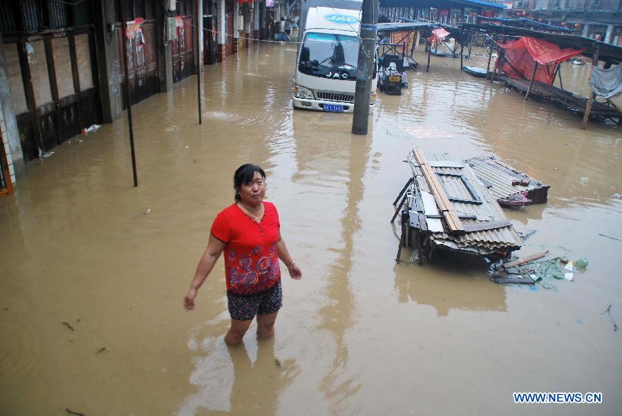 A woman stands inside a flooded market in Suwan Town of Chaohu City, east China's Anhui Province, July 7, 2013. The northern areas of Chaohu were hit by rainstorm on Monday morning, causing severe damage to local residents. (Xinhua/Su Zishan)