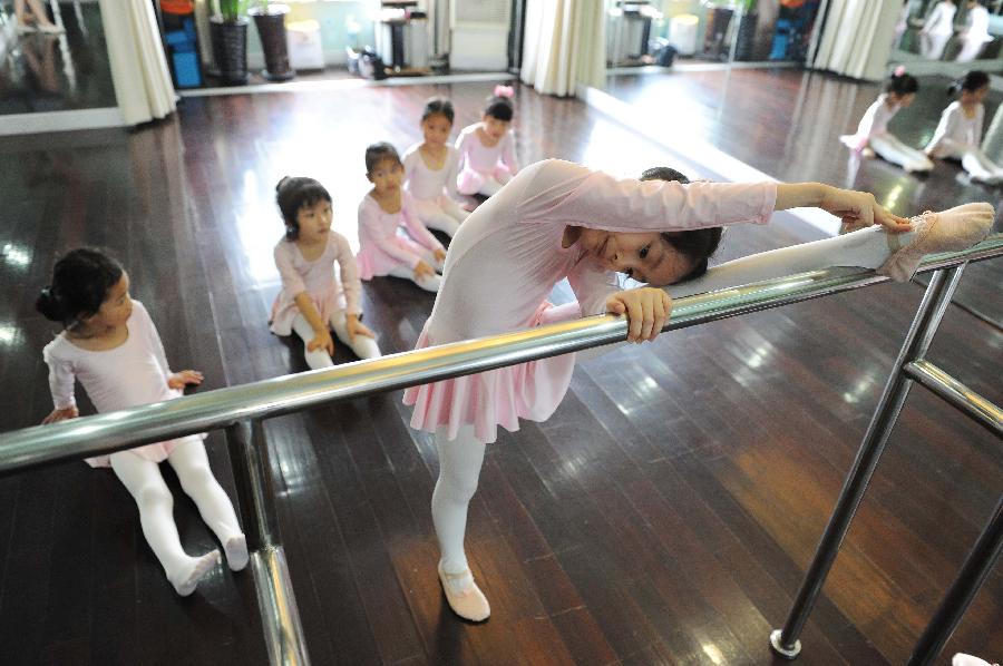 A young girl does physical training at a dance class during the summer vacation in Shanghai, east China, July 7, 2013. (Xinhua/Lai Xinlin)