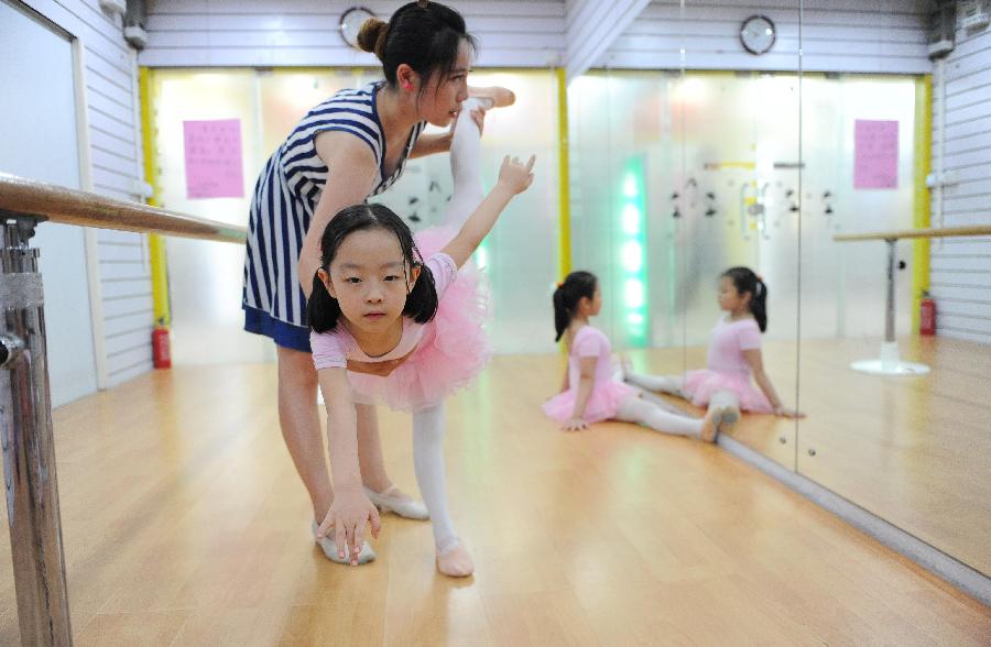 A teacher helps a young girl to practise dance at a dance training class during the summer vacation in Shanghai, east China, July 7, 2013. (Xinhua/Lai Xinlin)