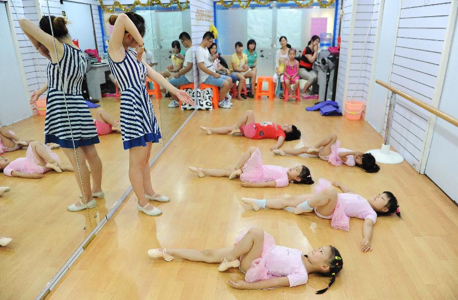 A teacher helps young girls to practise dance at a dance training class during the summer vacation in Shanghai, east China, July 7, 2013. (Xinhua/Lai Xinlin)