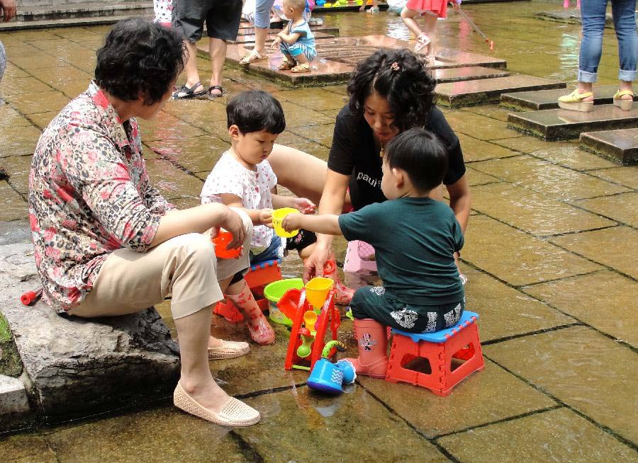 Parents and kids spend time in waterside leisure zone to beat the heat in the Wulongtan Park in Jinan, capital of east China's Shandong Province, July 8, 2013. The highest temperature in urban Jinan hit 35 degrees Celsius on Monday. (Xinhua/Xu Suhui)