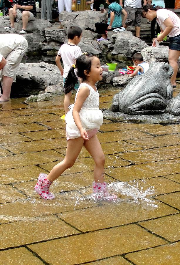 A child enjoy herself in waterside leisure zone to beat the heat in the Wulongtan Park in Jinan, capital of east China's Shandong Province, July 8, 2013. The highest temperature in urban Jinan hit 35 degrees Celsius on Monday. (Xinhua/Xu Suhui) 