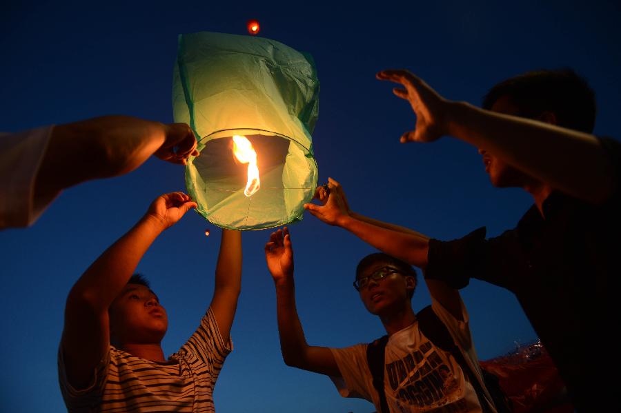 Several students fly a Kongming lantern to mourn the death of Wang Jialin and Ye Mengyuan, two young girls killed in a crash landing of an Asiana Airlines Boeing 777 at San Francisco airport, by the riverside in Jiangshan City, east China's Zhejiang Province, July 8, 2013. Local residents gathered at Xujiang Park in Jiangshan to show their grief to the 17-year-old Wang and 16-year-old Ye, who were students from Jiangshan High School. (Xinhua/Han Chuanhao)