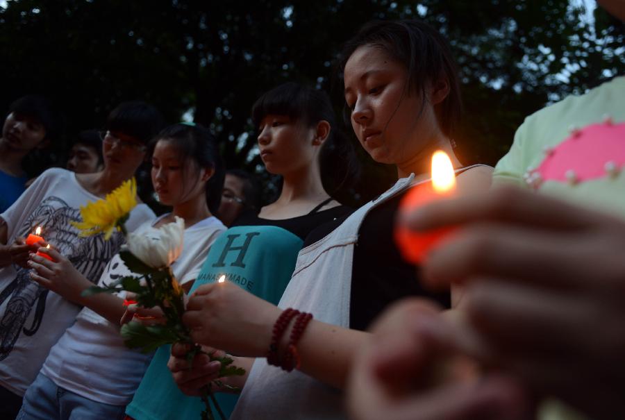 Students light candles to mourn the death of Wang Jialin and Ye Mengyuan, two young girls killed in a crash landing of an Asiana Airlines Boeing 777 at San Francisco airport, in Jiangshan City, east China's Zhejiang Province, July 8, 2013. Local residents gathered at Xujiang Park in Jiangshan to show their grief to the 17-year-old Wang and 16-year-old Ye, who were students from Jiangshan High School. (Xinhua/Han Chuanhao)