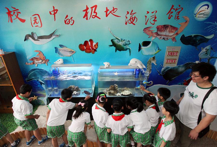 Children visit polar aquarium in the Hongqiao District Experimental Primary School in north China's Tianjin Municipality, July 8, 2013. The Hongqiao District Experimental Primary School Polar Aquarium, the first of its kind in Tianjin, opened on Monday. (Xinhua/Liu Dongyue)