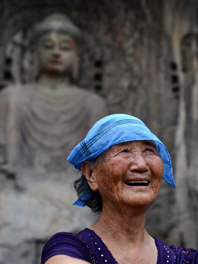 A tourist enjoys coolness in the scenic area of the Longmen Grottoes in Luoyang, central China's Henan Province, July 7, 2013. Recently, high temperature hit central China. Tourists relaxed in cool places in the Longmen Grottoes to avoid themselves from scorching weather. (Xinhua/Wang Song)