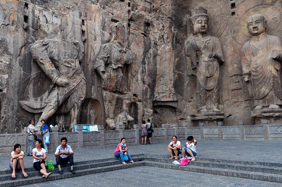 Tourists rest in the scenic area of the Longmen Grottoes in Luoyang, central China's Henan Province, July 7, 2013. Recently, high temperature hit central China. Tourists relaxed in cool places in the Longmen Grottoes to avoid themselves from scorching weather. (Xinhua/Wang Song)