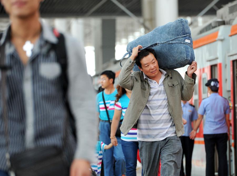 A passenger carrying luggage prepares to board the train at the Yinchuan Railway Station in Yinchuan, capital of northwest China's Ningxia Hui Autonomous Region, July 8, 2013. China's summer railway travel rush officially started on July 1 and will last until Aug. 31. (Xinhua/Peng Zhaozhi)