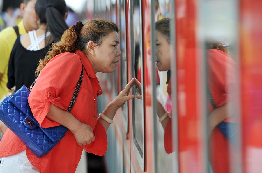 A woman sees her relatives off through the train window at the Yinchuan Railway Station in Yinchuan, capital of northwest China's Ningxia Hui Autonomous Region, July 8, 2013. China's summer railway travel rush officially started on July 1 and will last until Aug. 31. (Xinhua/Peng Zhaozhi)