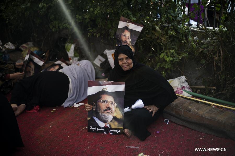 A supporter of ousted Egyptian president Mohamed Morsi holds a poster of Morsi as she rests in a tent outside Raba al-Adwyia Mosque, in Nasr City, Cairo, capital of Egypt, July 8, 2013. (Xinhua/Li Muzi) 