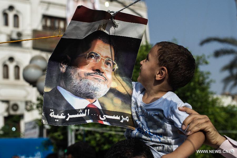 A child looks at a poster of ousted Egyptian president Mohamed Morsi outside Raba al-Adwyia Mosque, in Nasr City, Cairo, capital of Egypt, July 8, 2013. (Xinhua/Li Muzi)