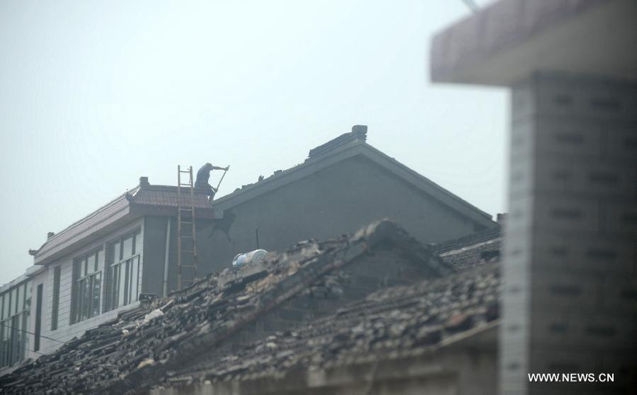 A villager mends a house roof damged by a tornado in Yuhu Village, Gaoyou City, east China's Jiangsu Province, July 8, 2013. Tornados battered Gaoyou and Yizheng in the province on July 7, making houses and power devices damaged. (Xinhua/Meng Delong)