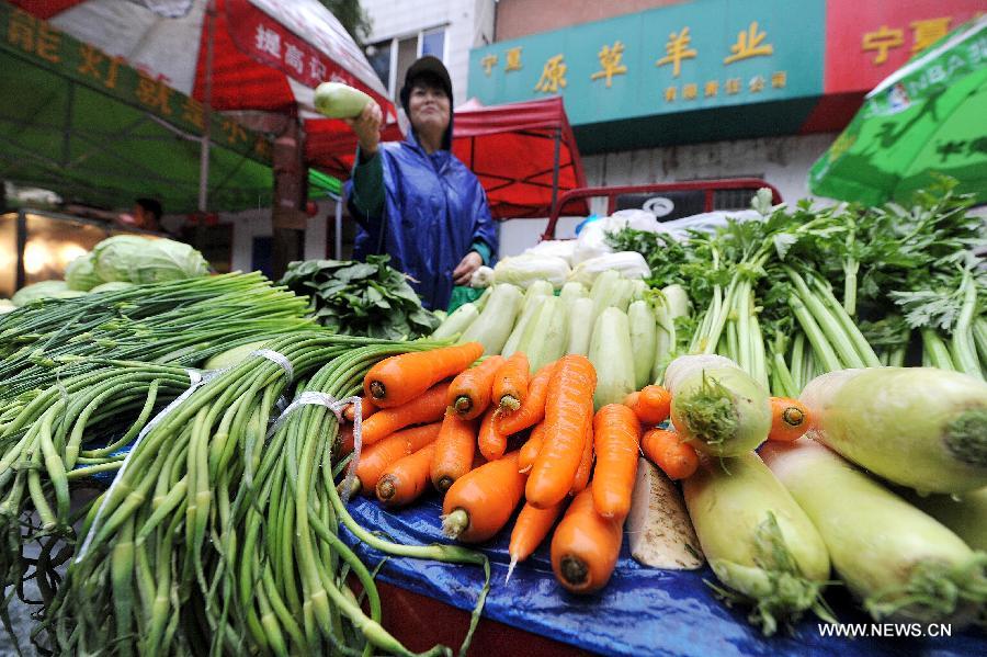 A seller picks vegetables for consumer at a market in Yinchuan, capital of northwest China's Ningxia Hui Autonomous Region, July 9, 2013. China's consumer price index (CPI), a main gauge of inflation, grew 2.7 percent year on year in June, up from 2.1 percent in May, the National Bureau of Statistics said on Tuesday. (Xinhua/Peng Zhaozhi) 