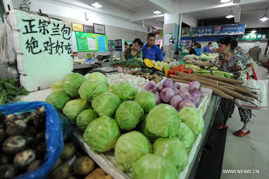 A citizen selects vegetables at a market in Hangzhou, capital of east China's Zhejiang Province, July 9, 2013. China's consumer price index (CPI), a main gauge of inflation, grew 2.7 percent year on year in June, up from 2.1 percent in May, the National Bureau of Statistics said on Tuesday. (Xinhua/Ju Huanzong) 