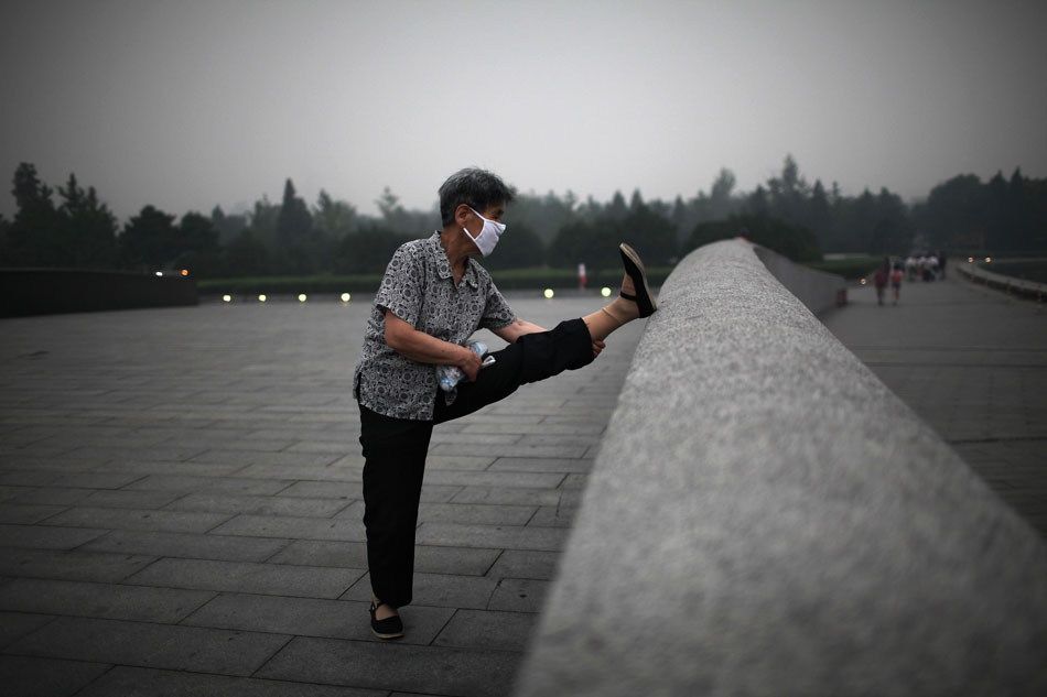 A mask-wearing woman takes exercise at dusk in Beijing on June 28, 2013. The city had been bathing in filthy air for four days since June 28 and a heavy rain and strong wind ended the hazardous air quality on last Monday night. (Xinhua/Jin Liwang)