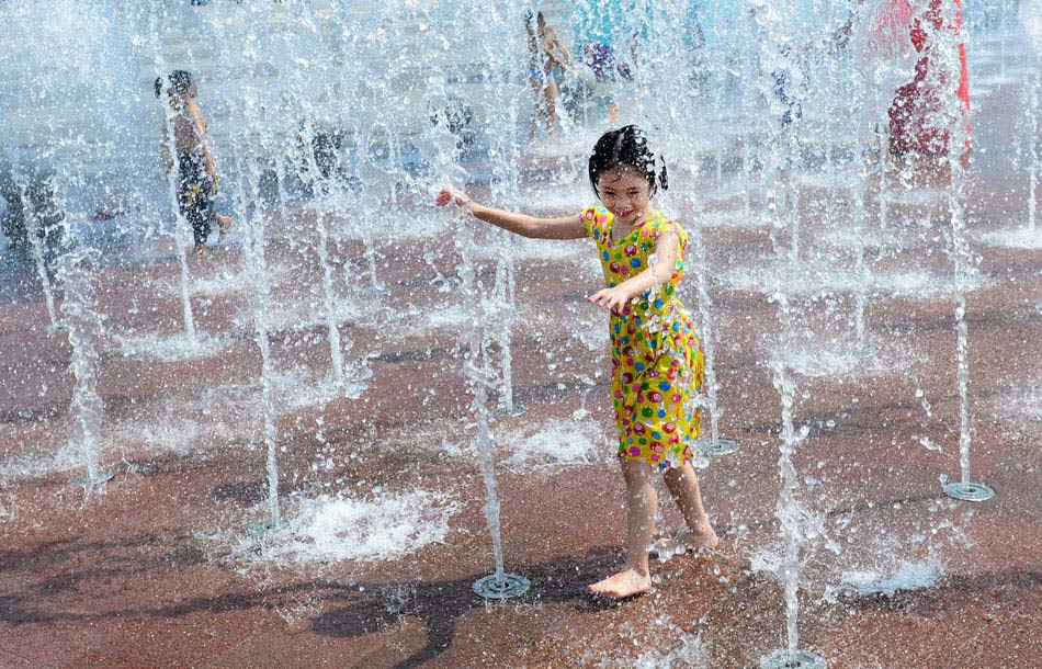 A toddler plays in a fountain in central China’s Wuhan city, June 29, 2013. The city had suffered from scorching heat and high humidity for days. (Xinhua/Cheng Min)