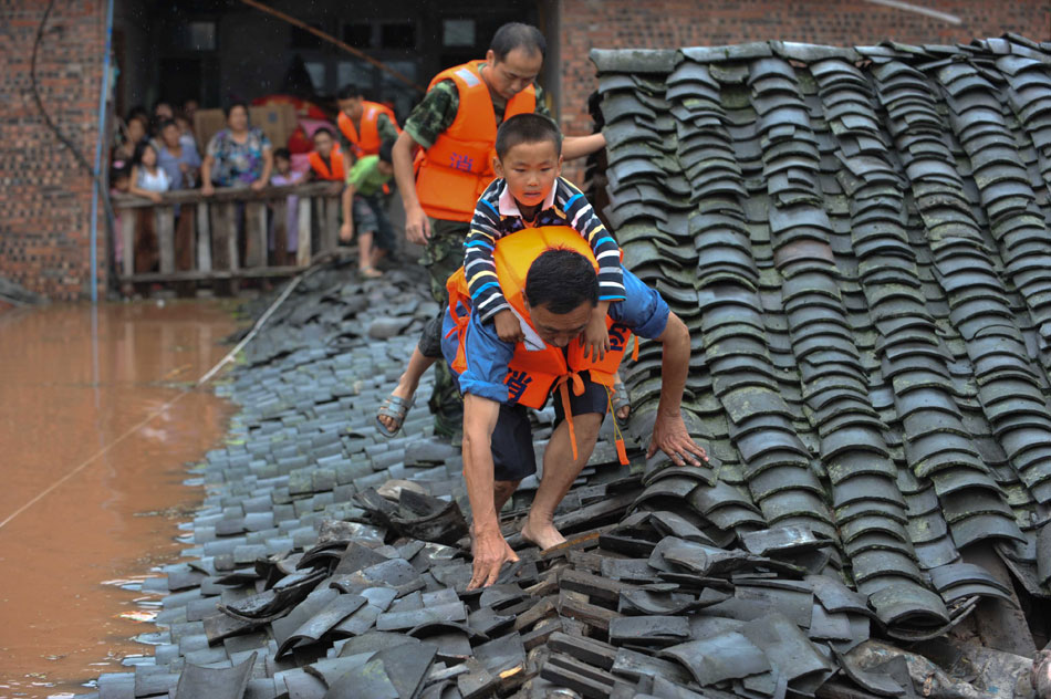 A boy rides on a fireman’s back to leave a flood-besieged building in southwest Chinese city Chongqing, July 1, 2013. Western part of Chongqing had been hit by heavy rains and the rising flood had left several counties in Chongqing submerged. (Xinhua/Liu Chan)