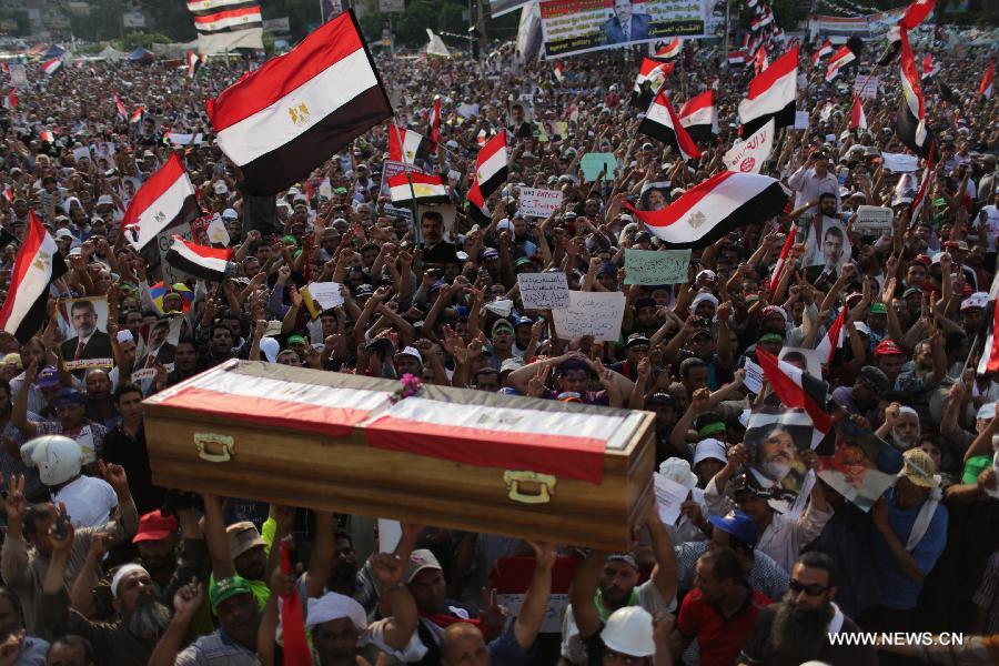 Supporters of ousted president Mohamed Morsi carry a coffin, one day after fellow protesters were killed in clashes, during a protest outside Rabaa al-Adawiya mosque in Cairo, Egypt, July 9, 2013. Clashes between Islamist protesters and the army in Cairo on July 9 killed at least 51 and injured 435 others. (Xinhua/Wissam Nassar) 
