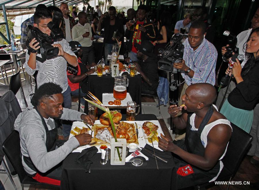 Four contestants take part in a burger challenge at Brew Bistro in Nairobi, capital of Kenya, July 9, 2013. Four contestants had one hour to finish a 5kg burger with beef, two huge burger buns and 40 toppings. Sauti Sol team won the burger challenge. (Xinhua/Li Jing)