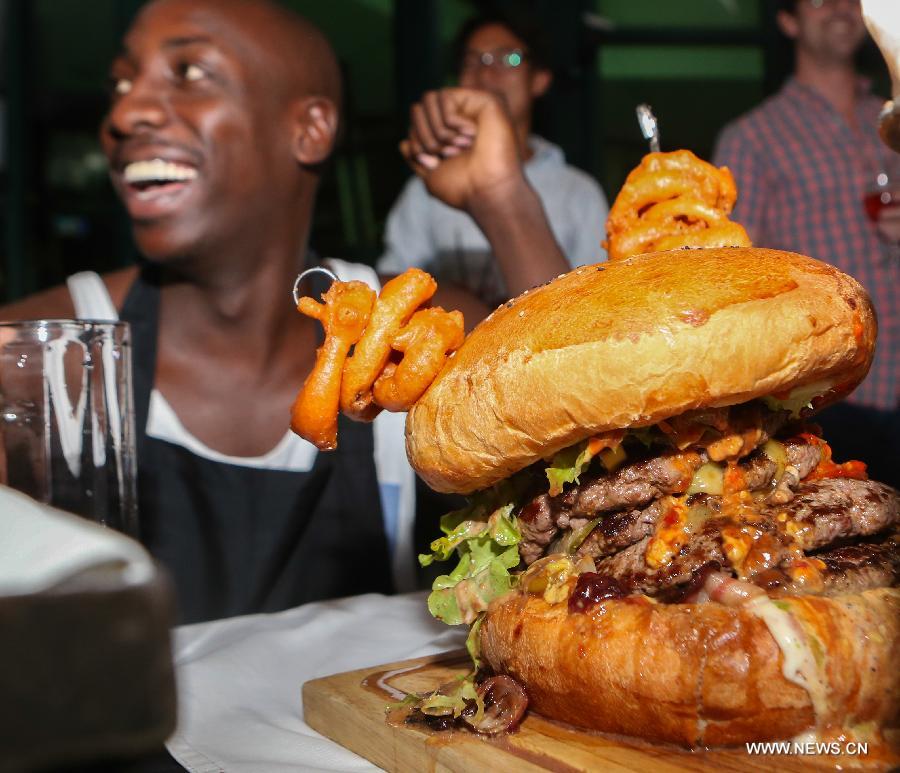 Photo taken on July 9, 2013 shows a big burger during a burger challenge at Brew Bistro in Nairobi, capital of Kenya. Four contestants had one hour to finish a 5kg burger with beef, two huge burger buns and 40 toppings. Sauti Sol team won the burger challenge. (Xinhua/Meng Chenguang)