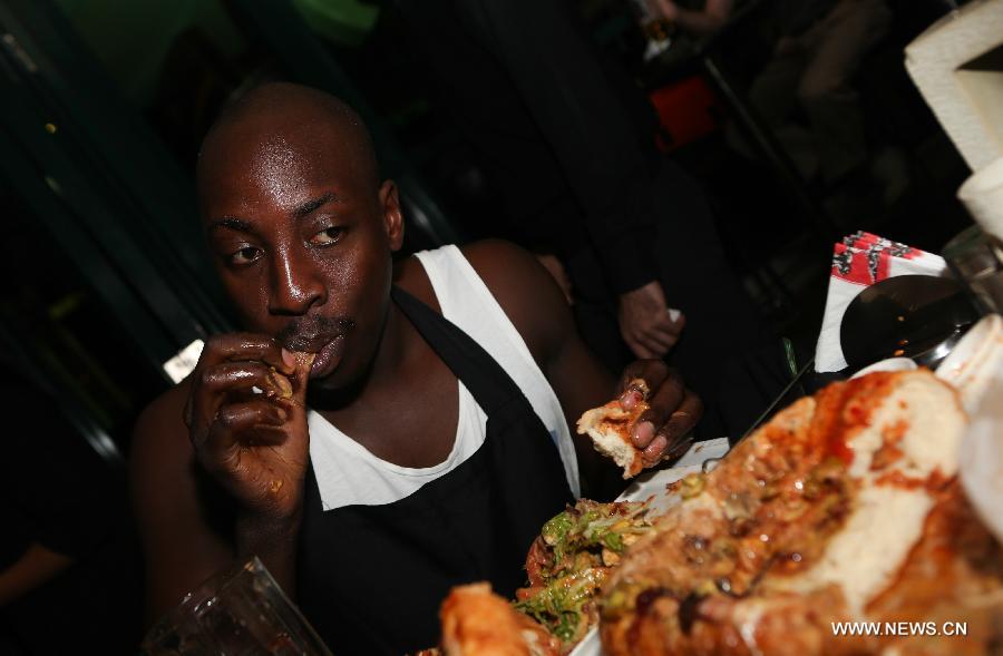 A contestant takes part in a burger challenge at Brew Bistro in Nairobi, capital of Kenya, July 9, 2013. Four contestants had one hour to finish a 5kg burger with beef, two huge burger buns and 40 toppings. Sauti Sol team won the burger challenge. (Xinhua/Meng Chenguang)