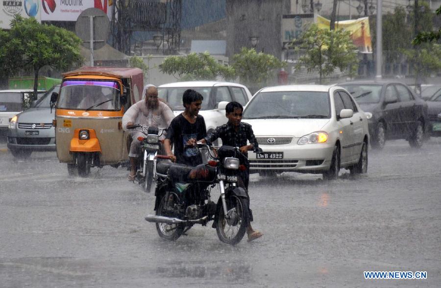 Two Pakistani children push a motorcycle during the heavy rain in eastern Pakistan's Lahore, July 9, 2013. Four people were killed and three others injured when a two-storey house collapsed due to heavy rainfall in Gujranwala city, near Lahore, in eastern Pakistan's Punjab province, local media reported Tuesday. (Xinhua/Sajjad)
