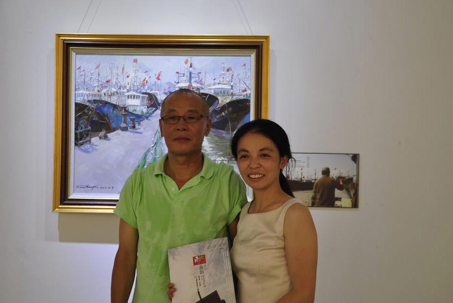 Chinese Australian oil painter Li Xiaozheng (L) and his wife Yingzi (R) pose before his work "Big Boats and Small Port" during the opening of his new exhibition themed "Jiangnan Charm" opened on July 7 at the Roundness Art Gallery in Beijing's Songzhuang, the largest art zone in both China and the world. The exhibition features 28 artworks created by Li during his 34-day fieldtrip, between March and April of this year, to Jiangnan. (China.org.cn/Zhang Junmian)