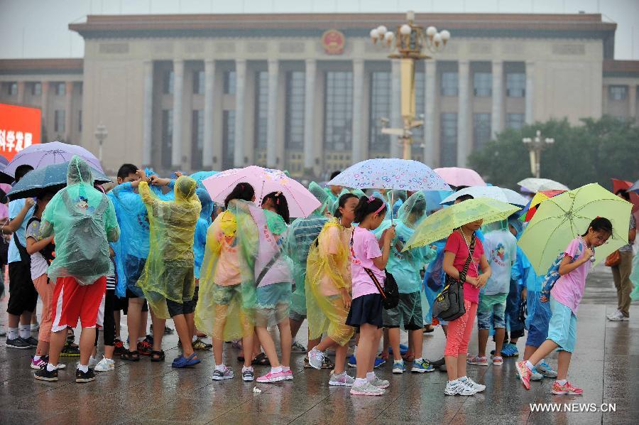 Children wearing raincoats and holding umbrellas visit the Tiananmen Square in Beijing, capital of China, July 9, 2013. Many tourists continue to come to enjoy the scenery of the capital city while Beijing witnessed frequent rainfall recently. The local meteorological observatory issued a warning on torrential rains from Tuesday to Wednesday in Beijing. (Xinhua/Chen Yehua)