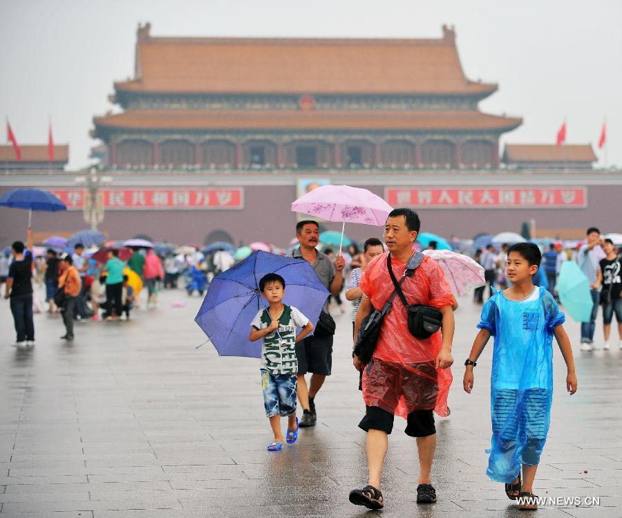People visit the Tiananmen Square in raincoats and under umbrellas in Beijing, capital of China, July 9, 2013. Many tourists continue to come to enjoy the scenery of the capital city while Beijing witnessed frequent rainfall recently. The local meteorological observatory issued a warning on torrential rains from Tuesday to Wednesday in Beijing. (Xinhua/Chen Yehua)