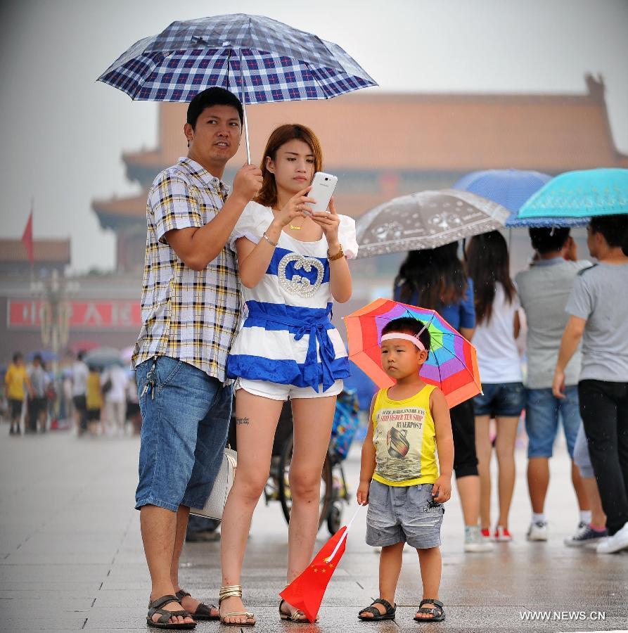 People holding umbrellas visit the Tiananmen Square in Beijing, capital of China, July 9, 2013. Many tourists continue to come to enjoy the scenery of the capital city while Beijing witnessed frequent rainfall recently. The local meteorological observatory observatory issued a warning on torrential rains from Tuesday to Wednesday in Beijing. (Xinhua/Chen Yehua)