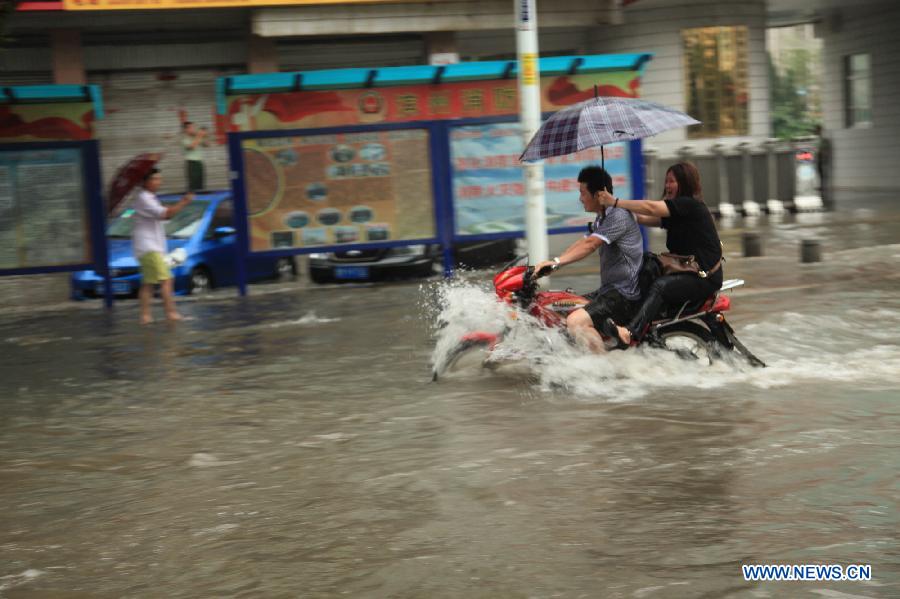Citizens ride on a flooded road in rainstorm-hit Binzhou City, east China's Shandong Province, July 10, 2013. (Xinhua/Liu Chunying)