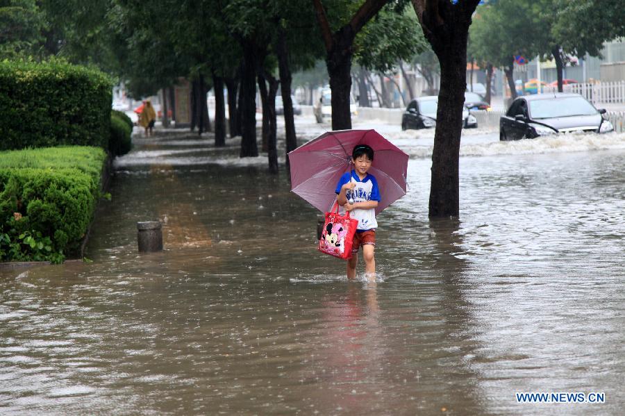 A child walks on a flooded road in rainstorm-hit Binzhou City, east China's Shandong Province, July 10, 2013. (Xinhua/Liu Chunying)