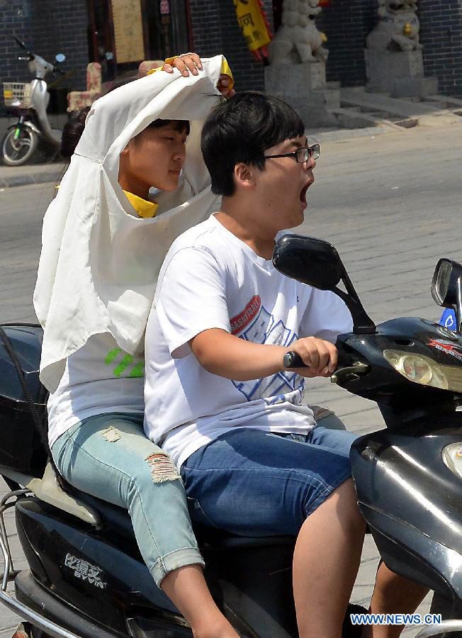 Citizens ride on a road as heat wave hits Shangqiu City, central China's Henan Province, July 10, 2013. The highest temperature reached 37 degrees Celsius in the city on Wednesday. (Xinhua/Wang Song)