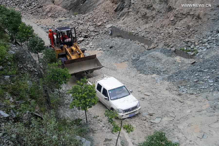 An excavator helps remove a trapped vehicle at the landslide-hit highway linking Wenxian County and Bikou Township in northwest China's Gansu Province, July 9, 2013. Rainstorms battered the region these days. (Xinhua) 