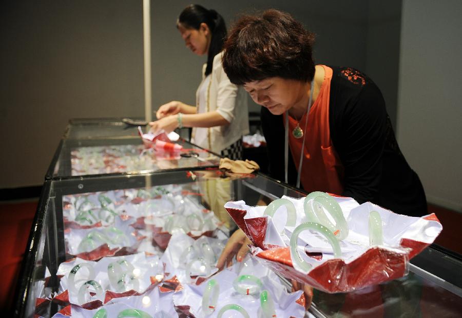 An exhibitor lays out jade bracelets at the 2013 China Pan-Asia Stone Expo in Kunming, capital of southwest China's Yunnan Province, July 10, 2013. The eight-day expo kicked off Wednesday at the Kunming International Convention and Exhibition Center. (Xinhua/Qin Lang)
