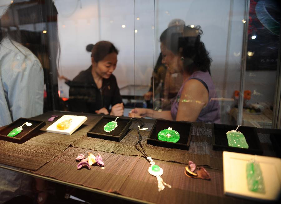 Visitors select jade accessories at the 2013 China Pan-Asia Stone Expo in Kunming, capital of southwest China's Yunnan Province, July 10, 2013. The eight-day expo kicked off Wednesday at the Kunming International Convention and Exhibition Center. (Xinhua/Qin Lang)
