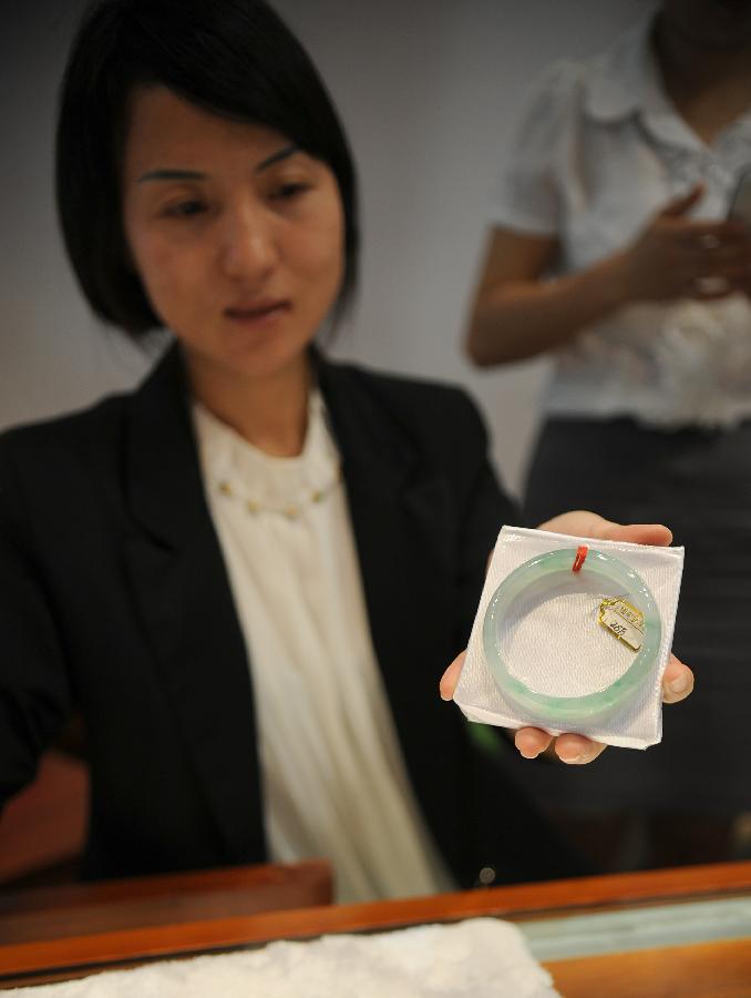 An exhibitor shows a jade bracelet at the 2013 China Pan-Asia Stone Expo in Kunming, capital of southwest China's Yunnan Province, July 10, 2013. The eight-day expo kicked off Wednesday at the Kunming International Convention and Exhibition Center. (Xinhua/Qin Lang)