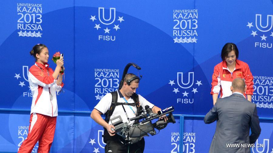 Jia Dongjin (1st L) of China takes photos of her teammate Zheng Shuangxue during the awarding ceremony for the women's 3m Springboard diving at the 27th Summer Universiade in Kazan, Russia, July 10, 2013. Zheng Shuangxue won the gold medal with 329.25. (Xinhua/Kong Hui)