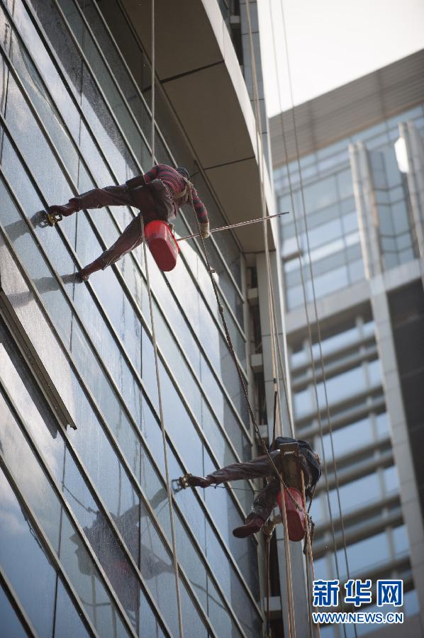 "Spider-men" brave the heat and clean the windows of a high-rise building in Guangzhou, capital of south China's Guangdong province on June 27, 2013. Cleansers of surface of high-rise building are also called "spider-men". (Photo/Xinhua) 