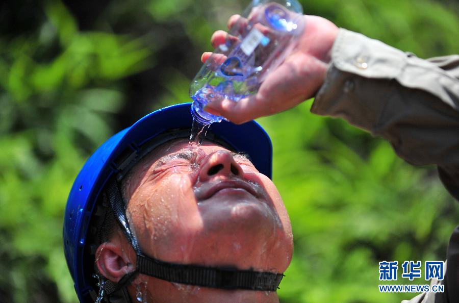 Ding Huilong uses mineral water to cool himself after finishing grid maintenance work on July 4, 2013, in Xiamen, southeast China's Fujian province. Ding is a worker with National Grid Transmission and Distribution Engineering Company of Fujian. (Photo/Xinhua)