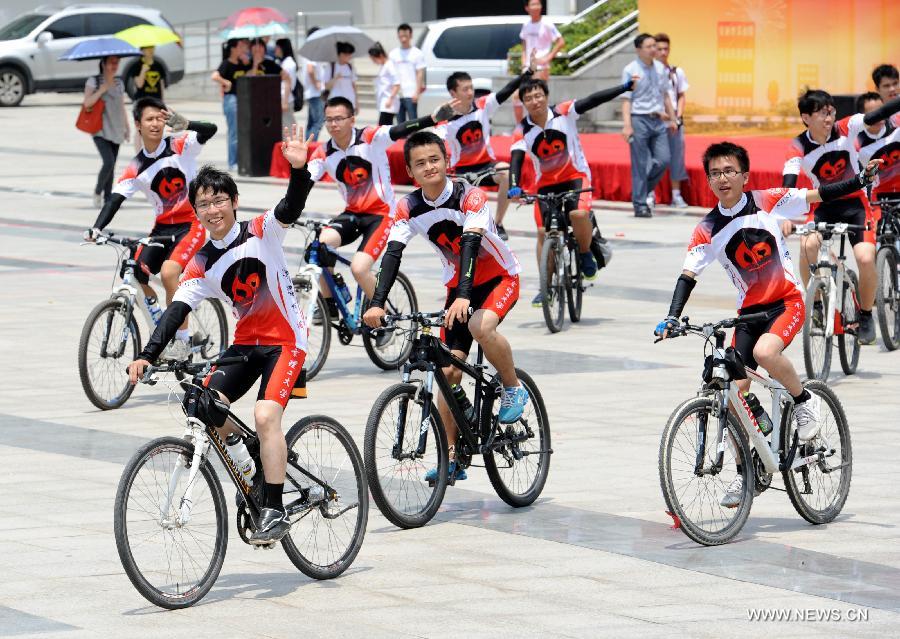 Cyclists wave to teachers and schoolmates before their expedition in Nanjing, capital of east China's Jiangsu Province, July 10, 2013. In celebration of the 60th anniversary of the founding of Nanjing University of Science and Technology(NUST), 15 students were selected to participate in a bike riding activity from Nanjing to Harbin where the old campus site was located. The roots of NUST can be traced back to 1952 when an institute of Military Engineering of the PLA was established. (Xinhua/Sun Can)