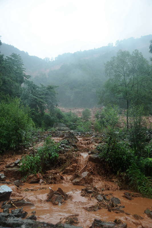 A rain-triggered landslide crushes roads in Zhongxing county, southwest China's Sichuan province on July 10, 2013. Rain-triggered mountain torrents and landslides buried 11 households, leaving two people dead and 21 missing. As of 9:45 p.m., 352 people stranded have been relocated to safe areas. (Xinhua/Liu Jie)